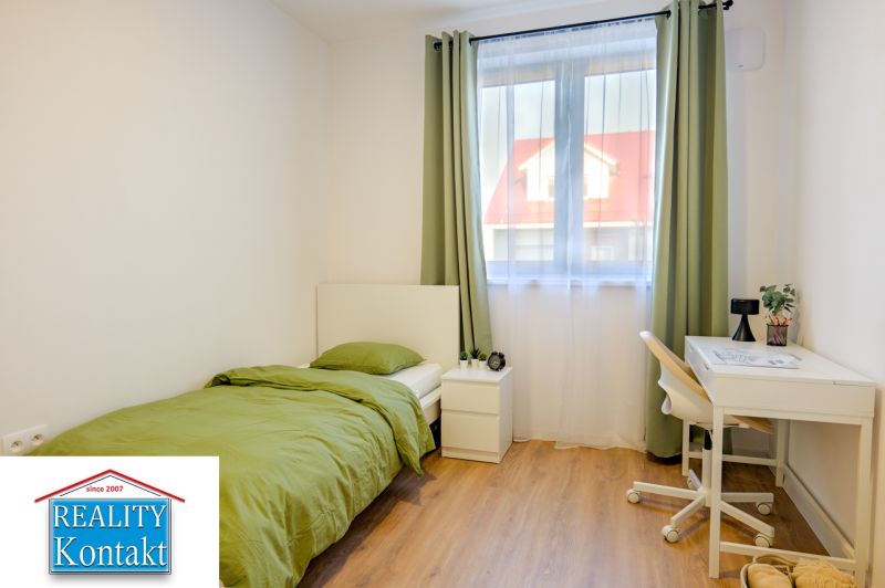 A room in a family house with a bed, a table, and a floor with a wooden decor.