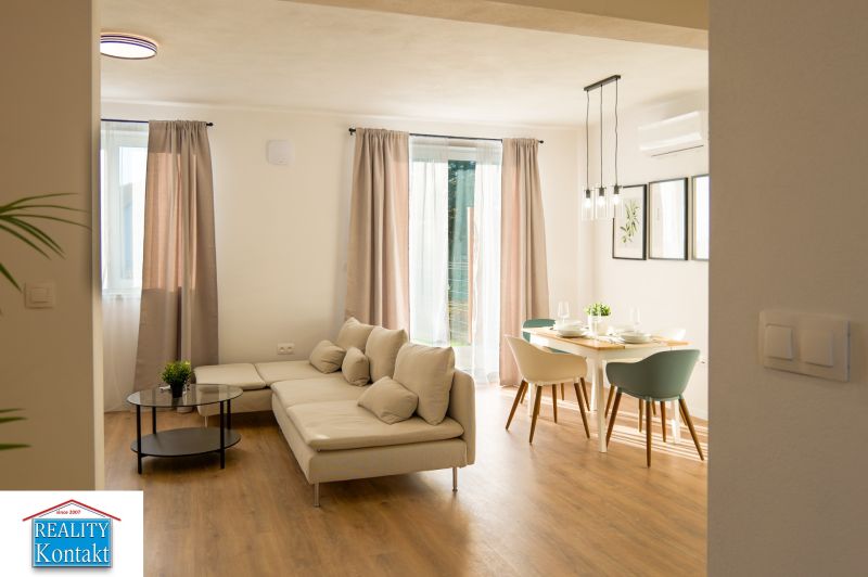 Living room with a corner sofa and a dining table on a floor with a wooden decor.