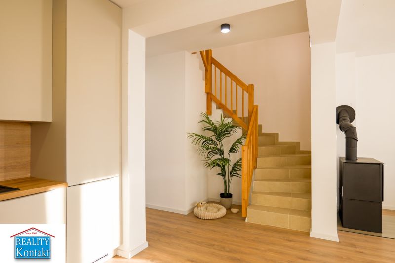 A family house with a wooden decor floor, a plant, and a staircase.
