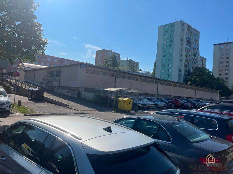 Parking lot near garages in Bratislava - Karlova Ves, Púpavová, surrounded by tall buildings.