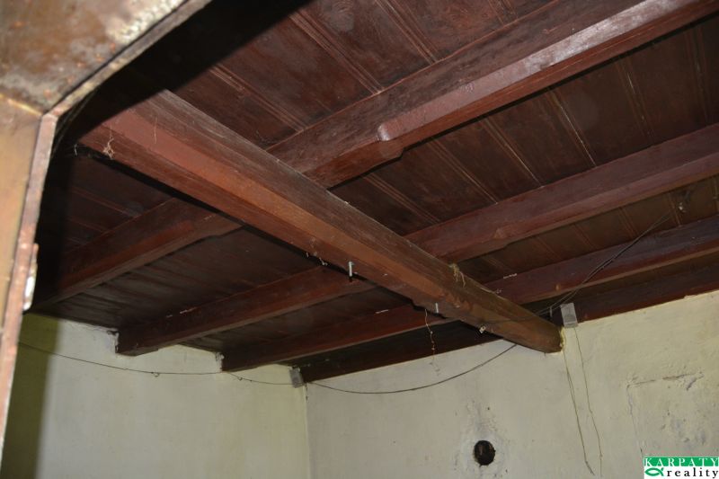 Wooden ceiling in the interior of a family house with rough plaster and electrical cables.