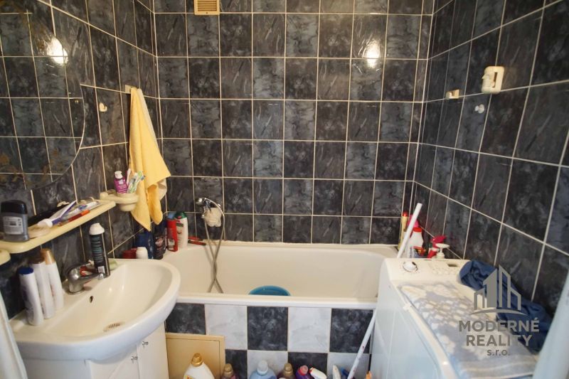 Bathroom in a 4-room apartment with dark tiles, a bathtub, and a sink.