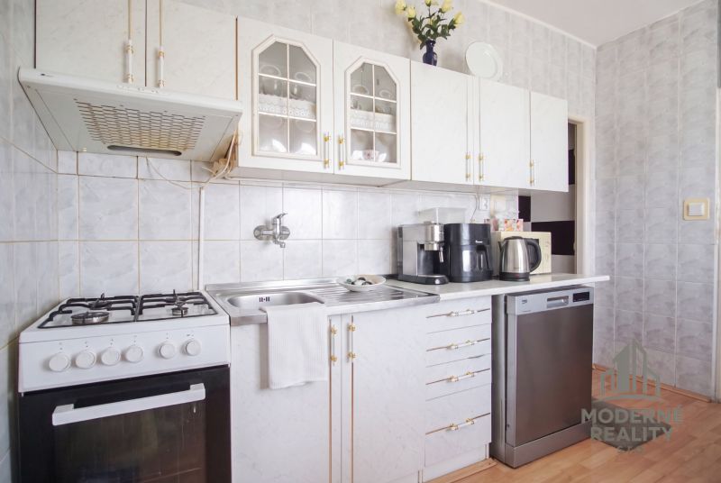 A kitchen in a 4-room apartment with a gas stove and white cabinets.