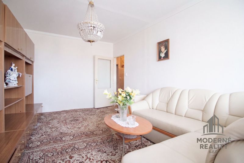 Living room in a 4-room apartment with a carpet pattern and a white sofa set.