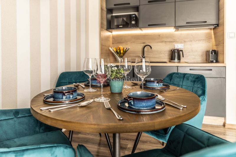 Dining table with placemats and glasses in a 2-room apartment, floor with wood decor.