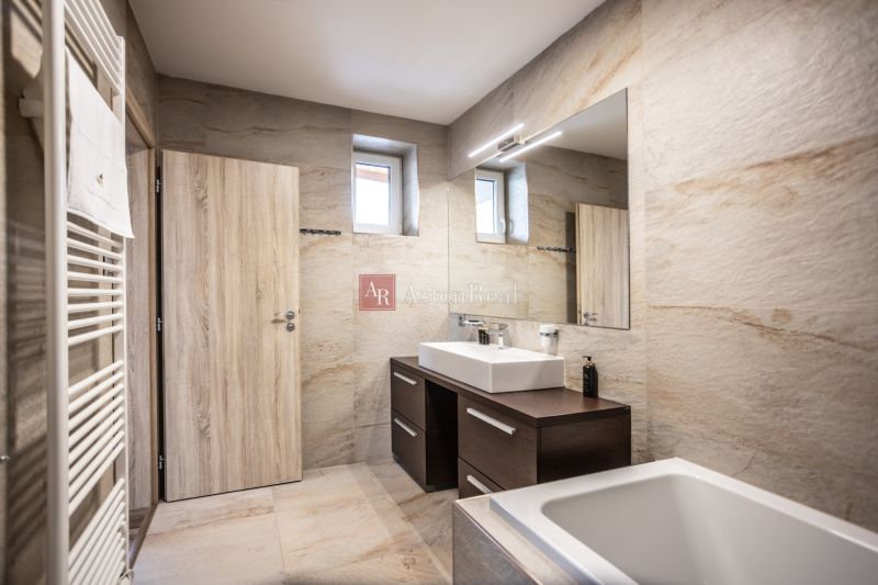 Bathroom in a 2-room apartment with light tiles, a mirror, and a sink.