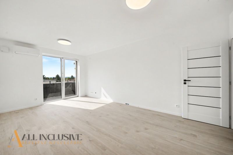 A bright room in a 2-room apartment with a wooden decor floor and large windows.