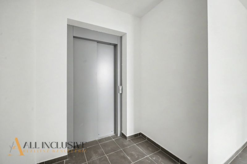 A hallway in a 2-room apartment with a gray elevator and tiles on the floor.
