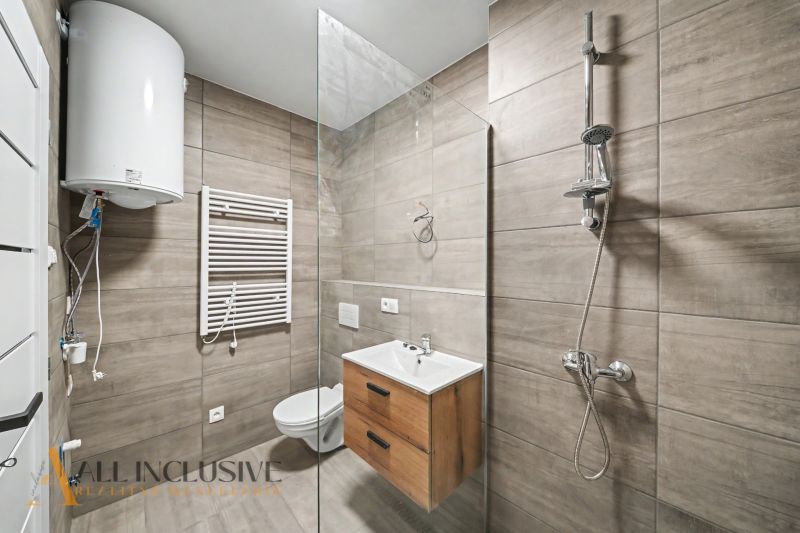Bathroom in a 2-room apartment with a shower, sink, and electric boiler.