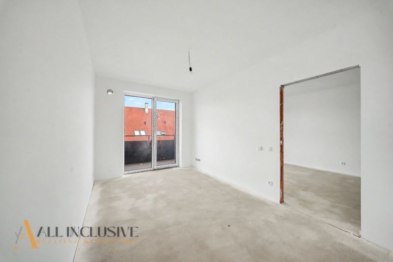 Empty rooms in a 2-room apartment with large windows and a view of the rooftops.