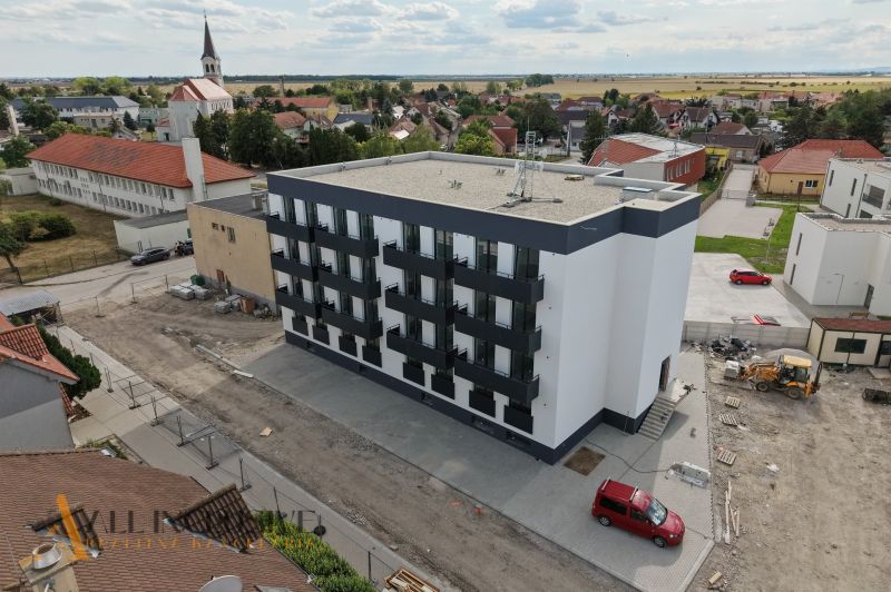 Zlaté Klasy: A view of a new building with 2-bedroom apartments and surrounding family houses.