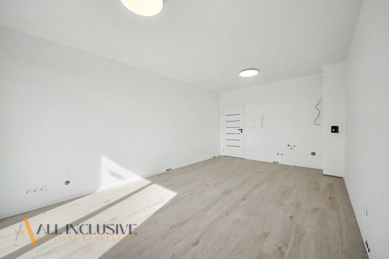 A room with white walls and a wooden decor floor in a 2-room apartment.