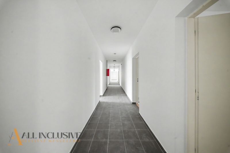 A long hallway in a 2-room apartment with light walls and a dark floor.