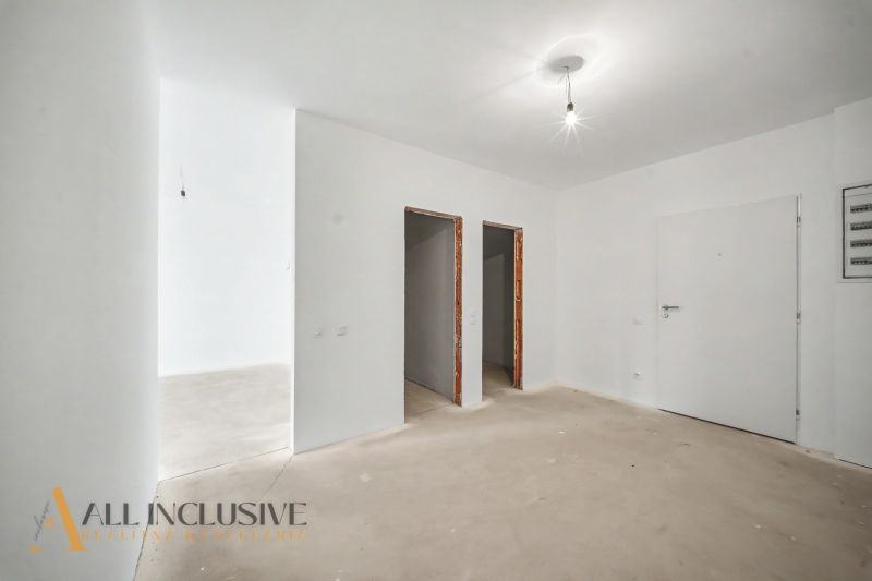 A white interior of a 2-room apartment with bare walls and ceiling lighting.
