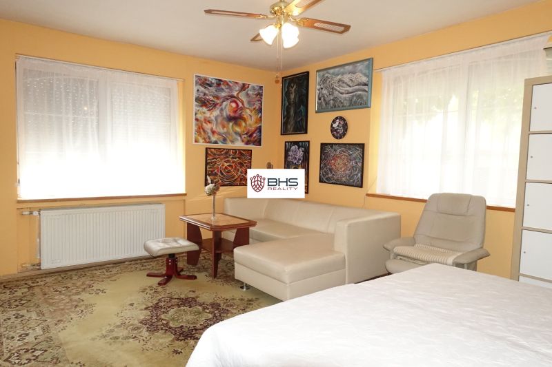 Living room in a family house with a sofa, an armchair, and art paintings on the wall.