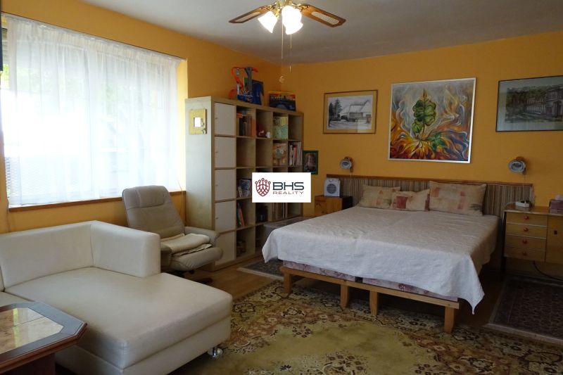 Bedroom in a family house with a large window, sofa, and wall paintings.