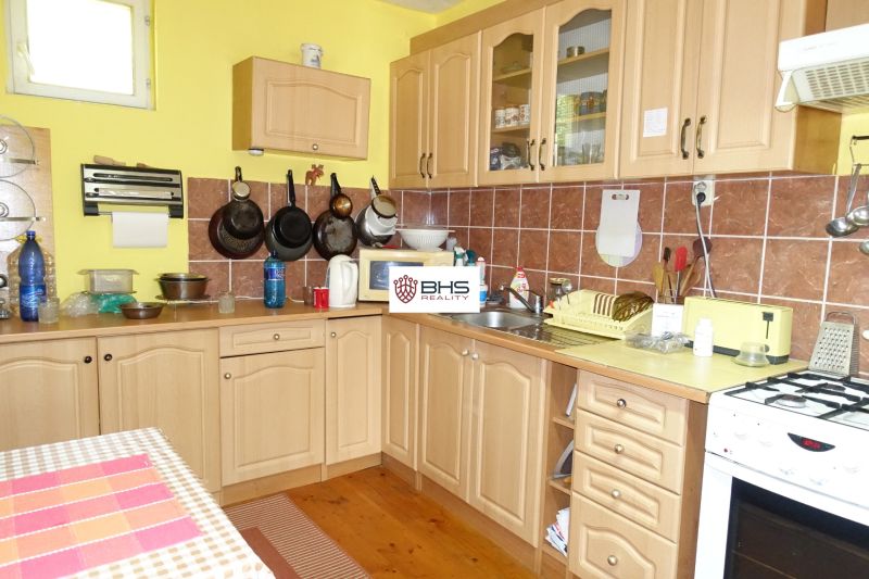 A kitchen in a family house with beige cabinets and a wood-patterned floor.