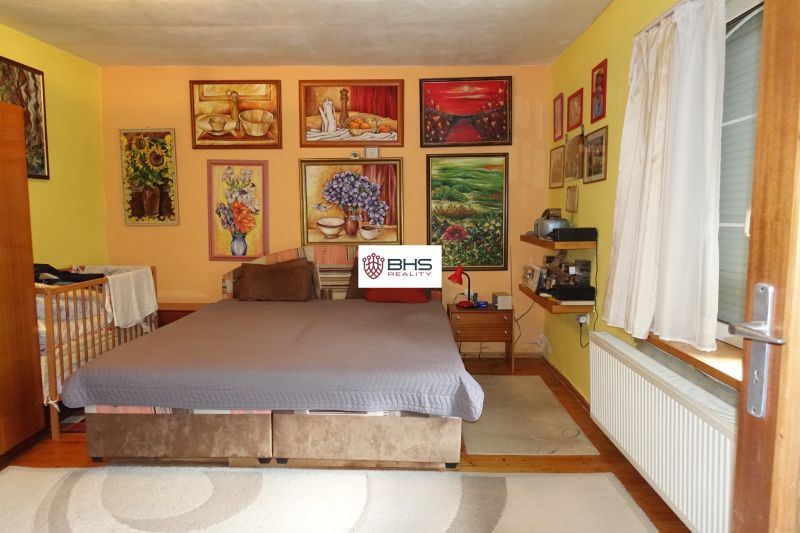 Bedroom in a family house with paintings on the walls and a floor with a wooden decor.