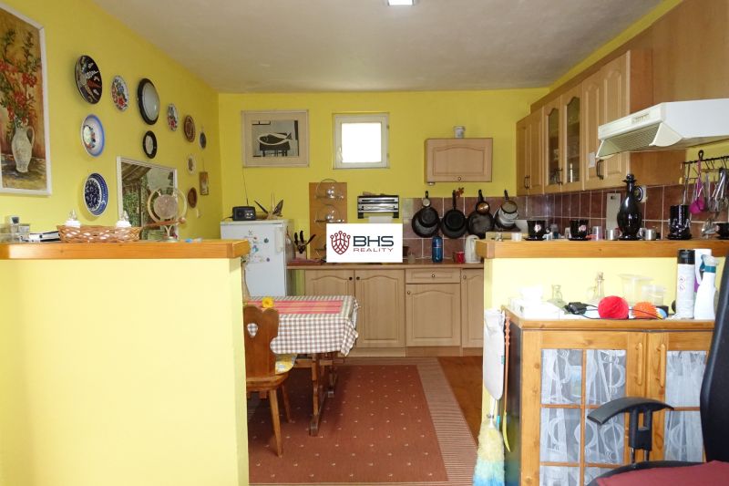 A kitchen in a family house with wooden decor, yellow walls, and decorative plates.