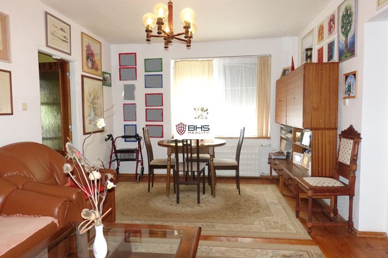 A living room in a family house with a wooden decor floor and paintings on the walls.