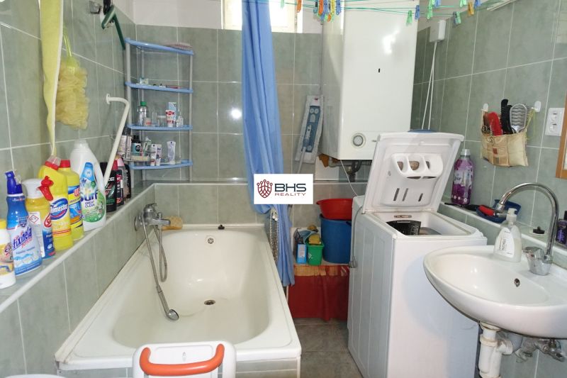 A bathroom in a family house with a bathtub, sink, and washing machine.