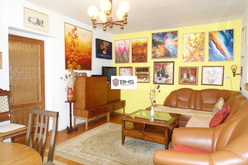 Living room in a family house with a leather sofa and colorful paintings on the walls.