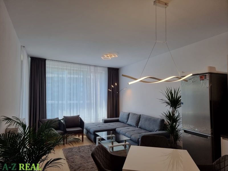 Living room in a two-room apartment with a wooden decor floor and stylish lighting.
