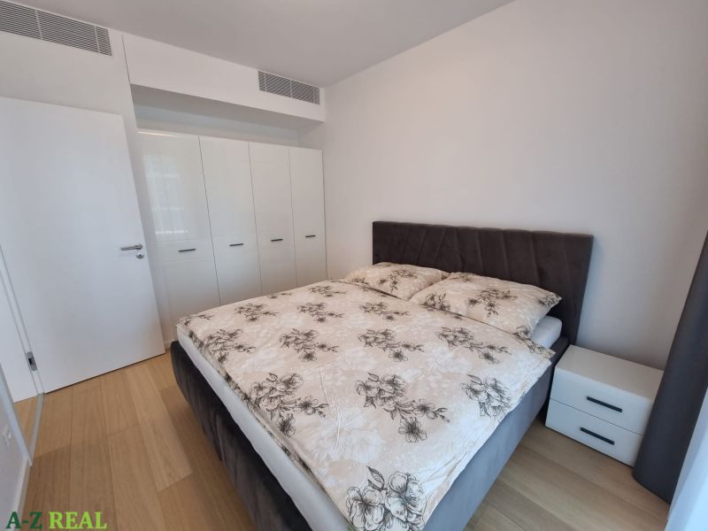Bedroom in a two-room apartment with a double bed and a built-in wardrobe, wooden decor flooring.