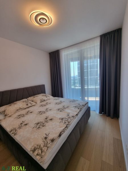 Bedroom in a 2-room apartment with a bed and a wooden decor floor.