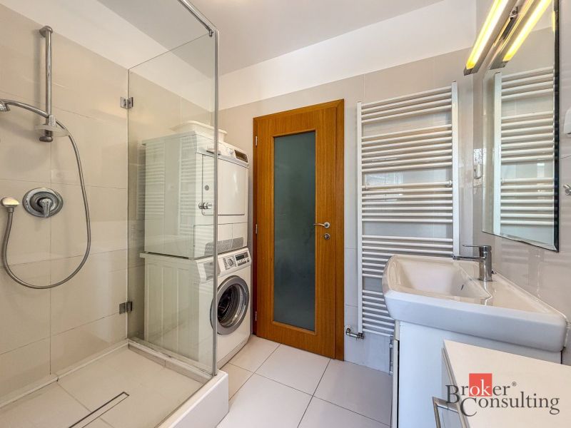 A bathroom in a 5 or more room apartment with a shower, washing machine, and dryer.
