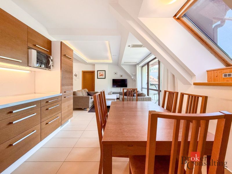 Dining table and kitchen in a 5 or more room apartment with a wood decor.