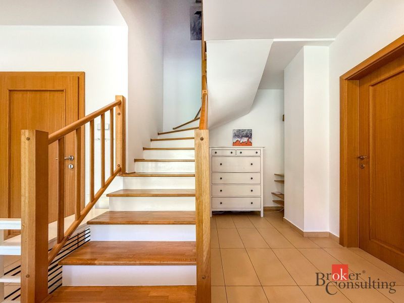 A staircase with a wooden railing and a floor with a wooden decor in a 5 or more room apartment.