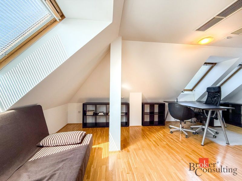 Attic room with a wooden decor floor, a desk, and a sofa in a 5 or more room apartment.