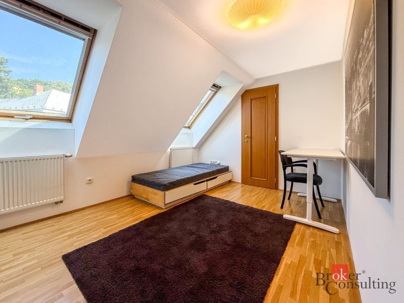 A bright room with dormer windows, a bed, and a table in a 5 or more room apartment.