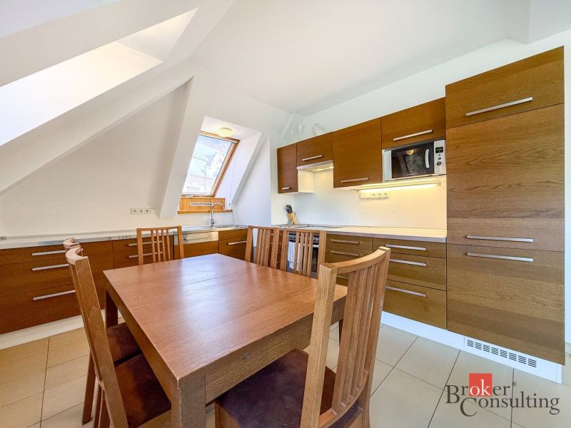 A kitchen in a 5 or more room apartment with a wooden decor floor and an attic window.