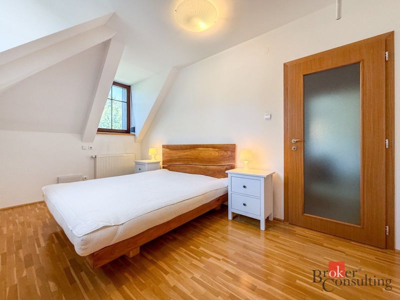 A bedroom with a wood-patterned floor in a five or more room apartment.
