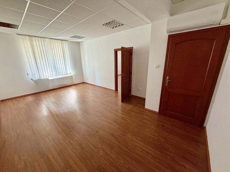 Windows and doors in an office with wood-patterned flooring and blinds.