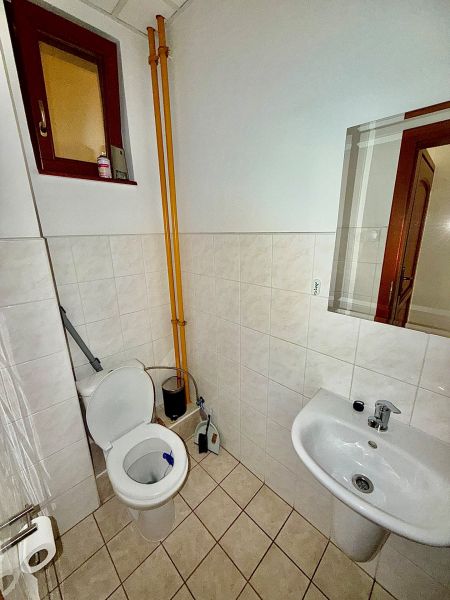 Bathroom in offices with a toilet, sink, and window.
