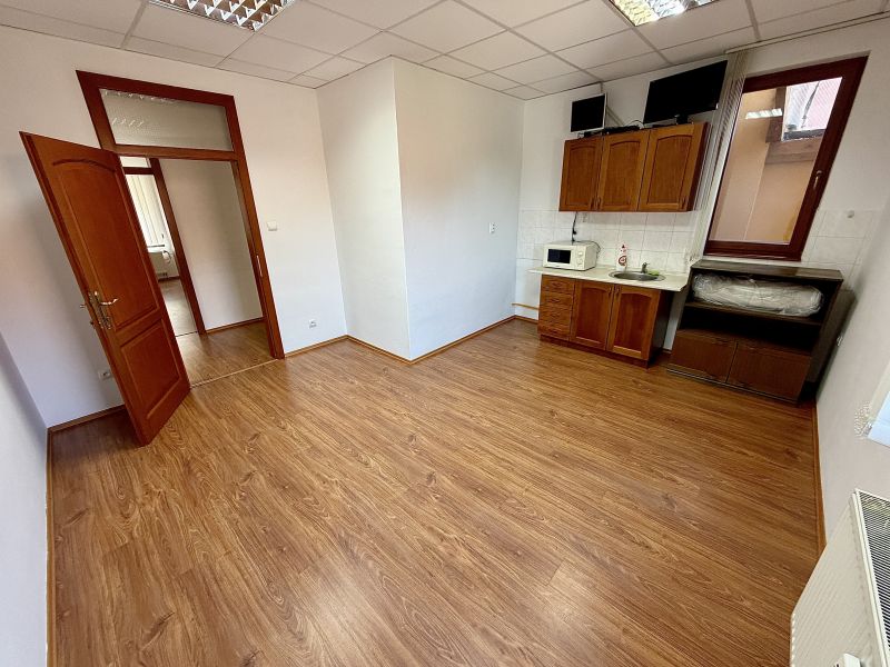 An office interior with wood-patterned flooring and a kitchenette.
