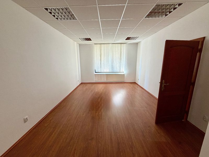 Offices with wood-patterned flooring, white walls, window with vertical blinds.