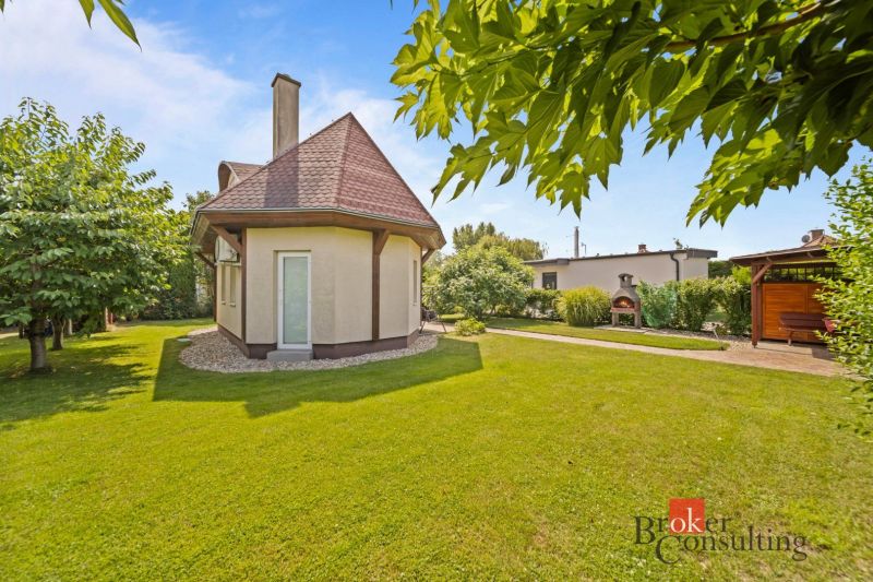 A cottage in Vojka nad Dunajom surrounded by a landscaped garden with trees and a gazebo.