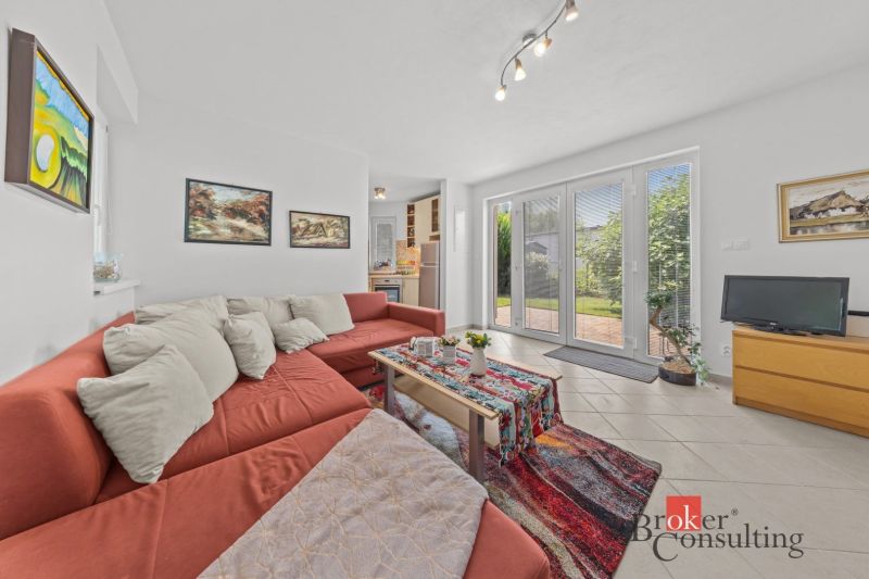 A bright cottage with an orange sofa and carpet, decorated with paintings and accessories.