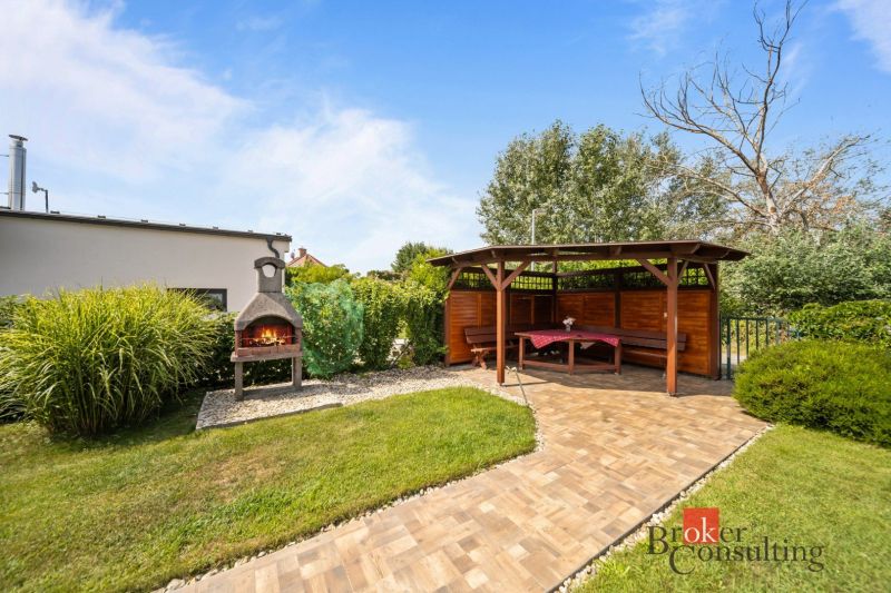 A gazebo with a garden fireplace by the cottage in Vojka nad Dunajom, surrounded by greenery and lawn.