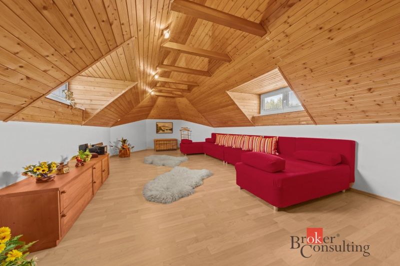 Attic interior of a cottage with a sofa set and wooden decor flooring.