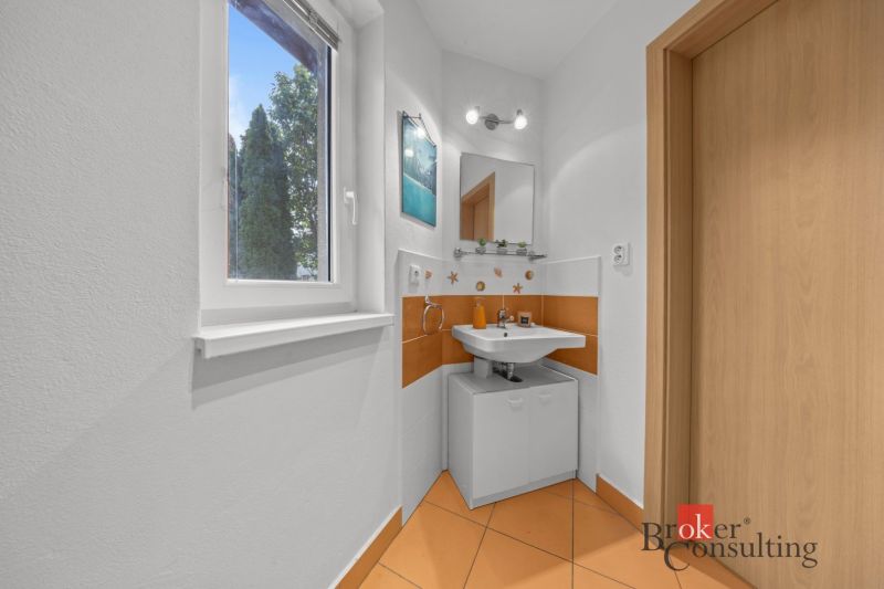 A bathroom with orange tiles, a sink, and a window, the cabin offers a compact space.
