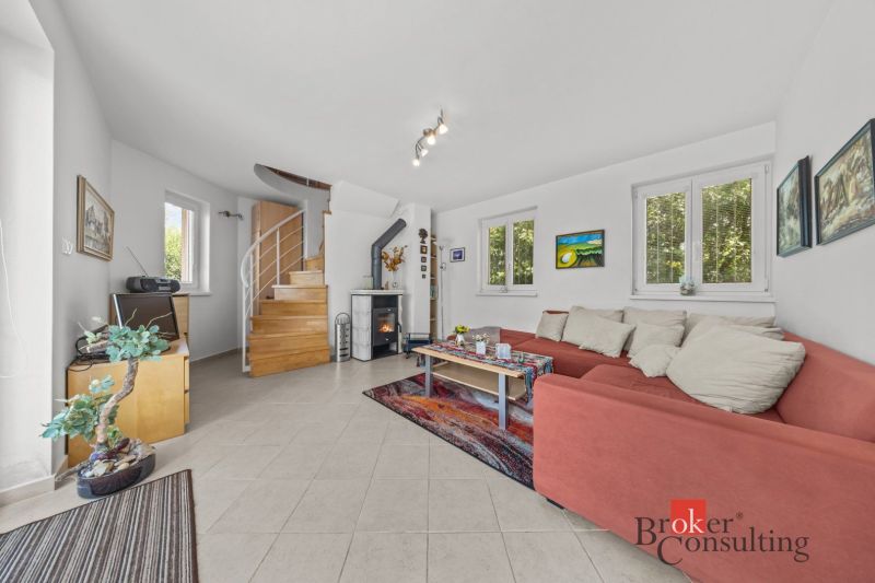 A cottage with a comfortable red sofa and a fireplace, complemented by a staircase and decorative elements.