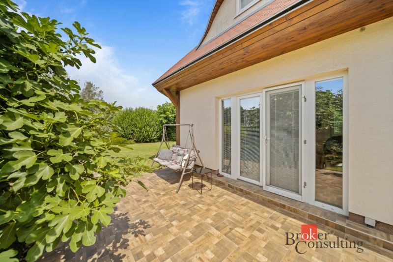 Terrace of a cottage in Vojka nad Dunajom with a swing and greenery in the background.