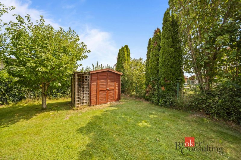 A garden by the cottage in Vojka nad Dunajom with a green lawn and a small wooden house.