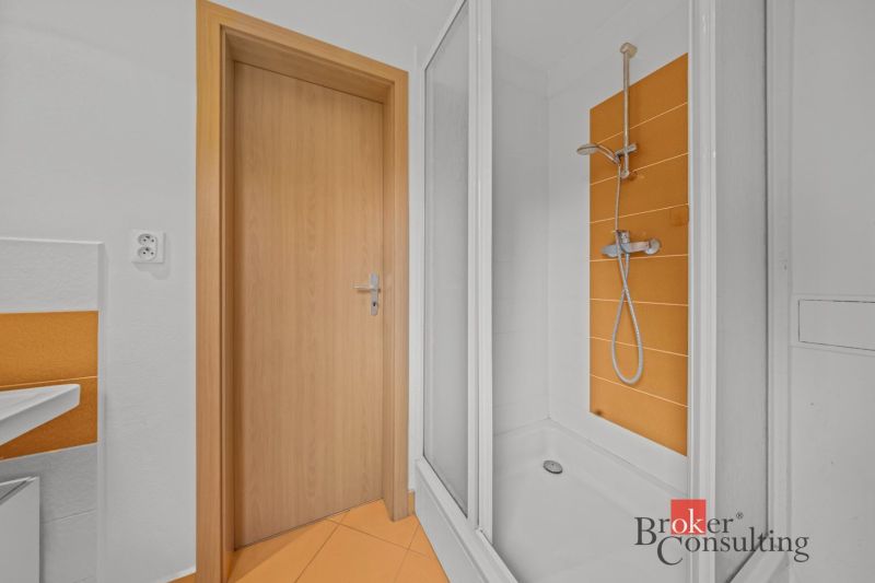 A bathroom with orange tiles and a shower in a cottage.