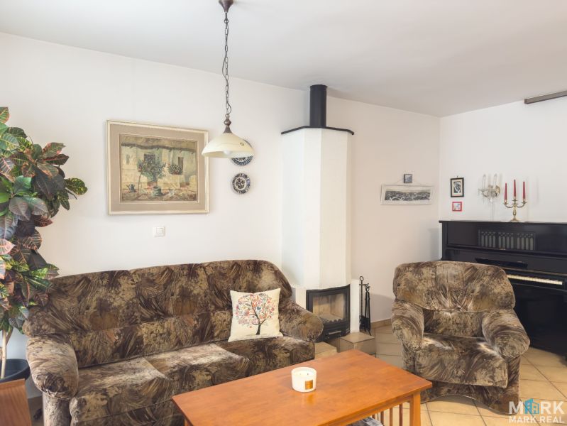 Living room in a family house with a sofa, fireplace, piano, and wall decorations.